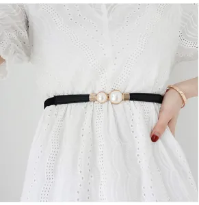 Close-up detail shot of a women's black elastic pearl waist belt paired with a white dress.