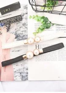 Detailed view of women's skinny waist belts with elegant pearl double buckles, black and white.