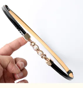 Slim black PU leather belt for women, featuring a golden metal and pearl decorative link.