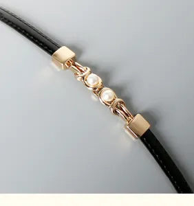 Close-up of women thin black belt detail with gold metal chain and double pearl buckle accent.