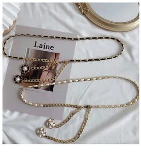 Details of vintage style metal chain belt with black white leather weave and pearl camellia charms.