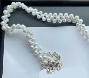 Detailed view of multi-strand faux pearl waist chain with exquisite metal flower clasp.