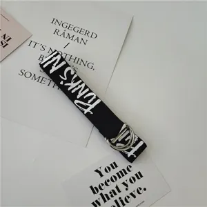 Black canvas belt featuring white letter print and double D-ring metal buckle for trendy style.
