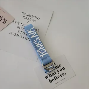 Canvas belt detail showing stylish letter print, durable blue fabric and silver metal D-rings.
