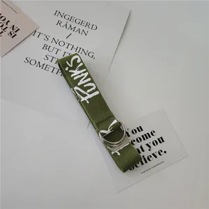 Detail view of green canvas belt with punk letter print and metal double ring buckle.