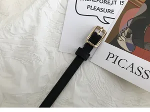 Minimalist women's thin black belt with gold square buckle, stylish accessory for trousers.