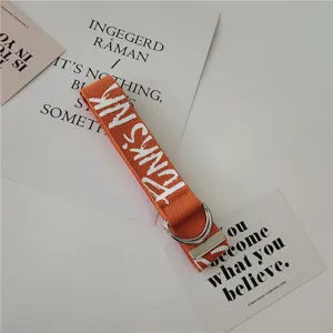 Orange canvas belt detail showing durable woven fabric, white print and metal double D-rings.