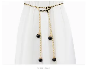 Close-up detail of a fashion women waist chain with black and gold interlaced chain and beads.