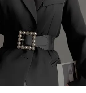 Detail shot of a wide black elastic waist belt featuring a chic square pearl buckle.