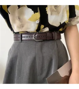 Stylish brown leather belt featuring double-row perforations paired with chic grey pleated trousers.