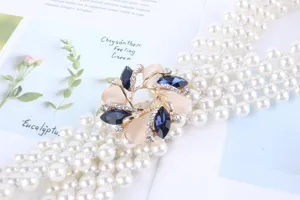 Gros plan détaillé de la ceinture de perles multicouche avec boucle fleurie en strass.
