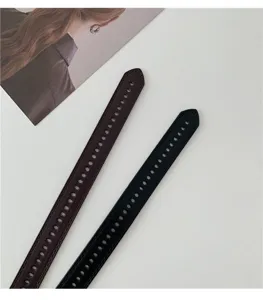 Close-up detail of multi-hole women's belts in black and dark brown with neat stitching.