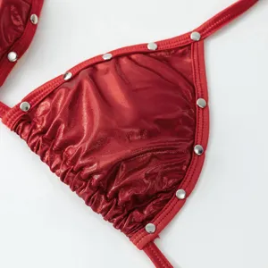 Red metallic bikini top detail, shiny fabric with silver stud embellishments, close-up shot