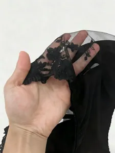 Close-up detail of black sheer mesh fabric featuring delicate floral embroidery for gothic fashion.