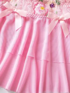 Close-up detail of pink mesh floral embroidery skirt with cute satin bows and ruffles.