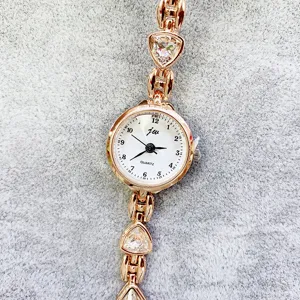 Detailansicht einer Damen Quarz Armbanduhr in Roségold mit Zirkoniasteinen und weißem Zifferblatt.