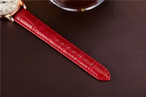 Close-up detail of luxury red embossed leather watch strap with rose gold case and dial.