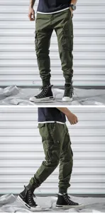 Detailed view of men's military green cargo pants with multiple pockets and cuffed hems.
