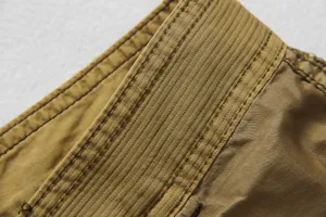 Men casual cargo pants detail closeup, premium khaki fabric with fine double stitching.