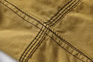 Close-up detail of durable khaki canvas fabric with heavy-duty contrast double stitching.