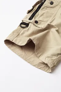 Close-up detail of men cargo shorts khaki fabric multi pocket design zipper metal hardware