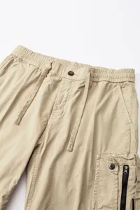Close-up detail view of men's casual khaki cargo pants waistband featuring drawstring and pocket.