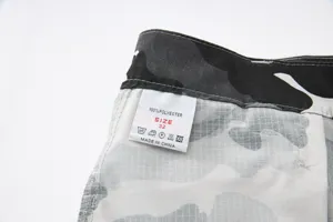 Men's camouflage cargo shorts detail view, showing size label and polyester material.