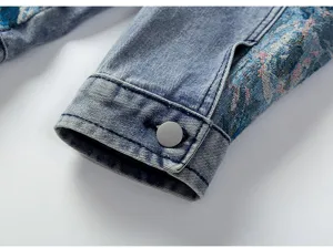 Gros plan sur le poignet de veste en jean avec patchwork brodé complexe et bouton en métal.