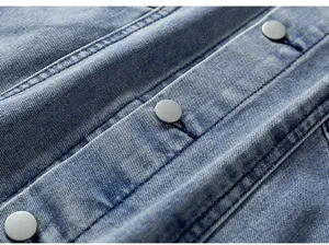 Gros plan détaillé de la veste en jean pour homme avec texture de couture et boutons en métal.