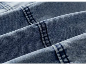Gros plan détaillé d'un tissu en denim bleu présentant des doubles coutures soignées.