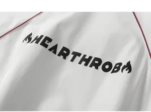 Modisches Detail einer weißen Herrenjacke mit roten Bändern und schwarzem Schriftzug.