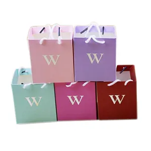 Close up of small colorful square paper gift bags detail view with handle and letter print.