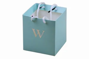 Square paper gift bag with white rope handles and gold letter W design for wedding candy.