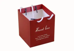 Red square paper gift bag candy box with white handles and sweet love print for party favors.