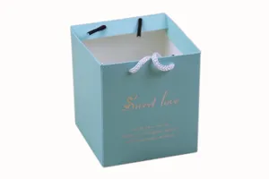 Light blue square paper gift bag and candy box with rope handles for wedding and party favors.
