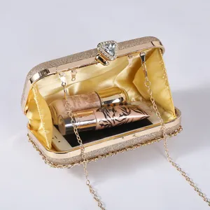 Élégant sac de soirée à paillettes dorées avec fermoir diamant et détail de chaîne.
