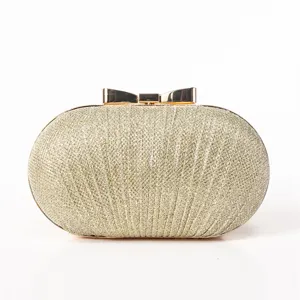 Gold glitter evening clutch bag detail view showcasing elegant metallic bow clasp design.