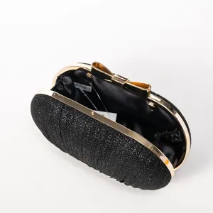 Detail view of the black glitter evening clutch bag with gold frame and bow clasp.