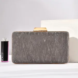 Detailaufnahme einer glitzernden grauen Abendtasche mit goldenem Metallverschluss.