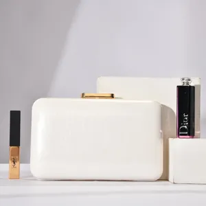 Elegant white evening clutch bag with glossy textured surface and gold metal clasp detail.