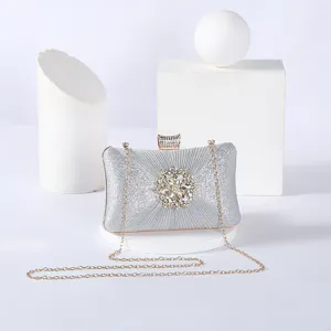 Silver glitter evening clutch bag with sparkling crystal flower clasp and gold chain strap.