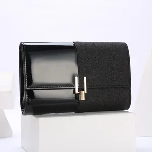 Black sequin and patent leather evening clutch bag detail showing gold metal lock.