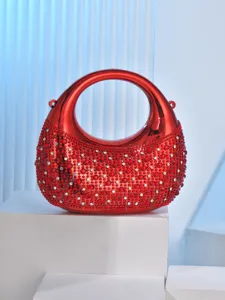 Red crescent acrylic evening bag with shimmering rhinestones, detailed close-up shot.