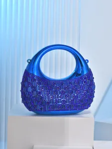 Blue metallic moon evening bag close-up showing rhinestone details and structured ring handle.