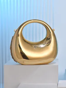 Gold metallic crescent evening bag detail showing smooth polished surface and rigid circular handle design.