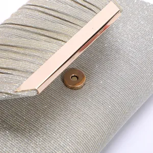Close-up detail of silver glitter pleated evening clutch bag with elegant rose gold metal clasp.