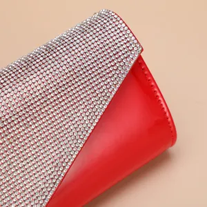 Close-up of red PU leather evening clutch with sparkling rhinestones detailed craftsmanship.