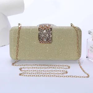 Élégant sac de soirée pochette dorée à paillettes avec fermoir strass et chaîne métallique.