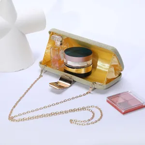 Vue détaillée de la pochette de soirée scintillante dorée avec chaîne et accessoires cosmétiques.