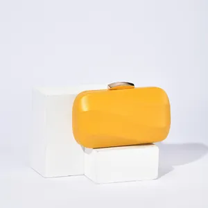 Yellow evening clutch bag detail showing sleek hard-shell design with metallic lock.